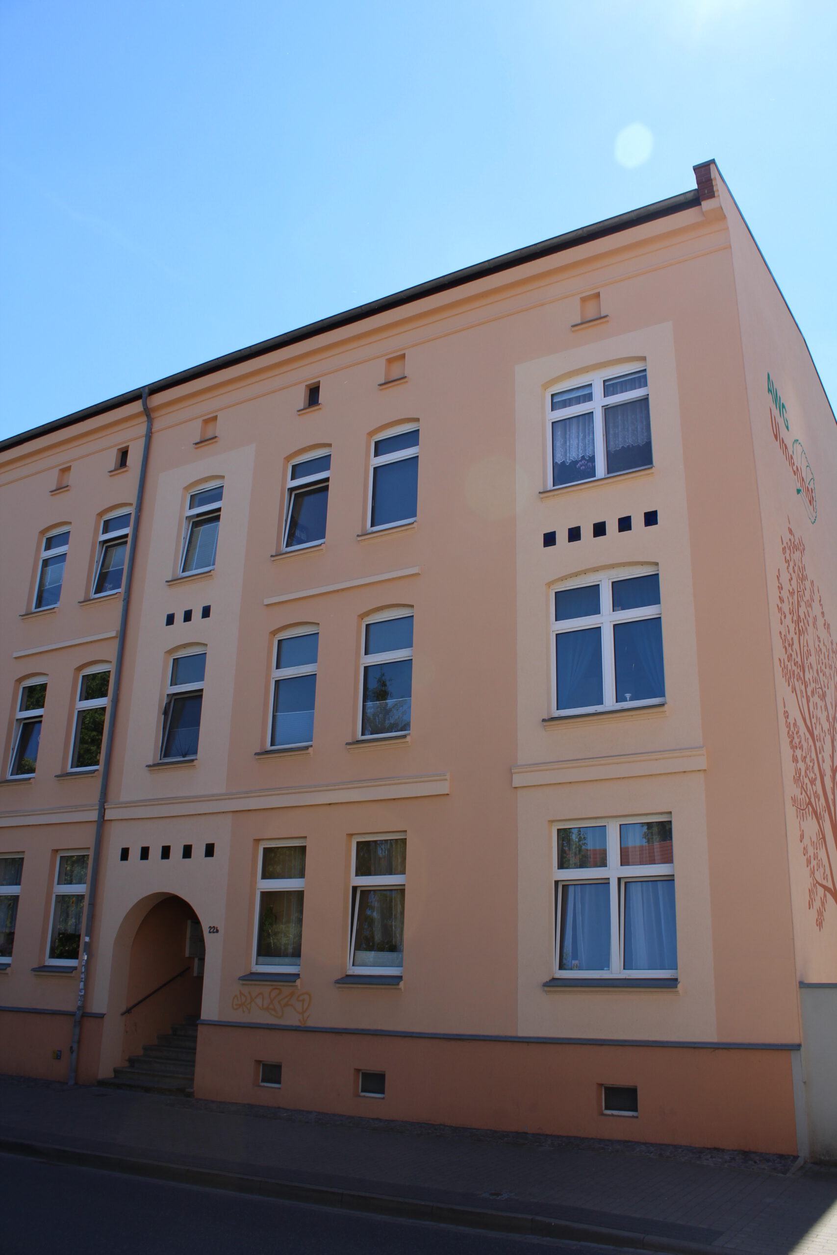 Sanierter AWG-Güstrow-Wohnhausbau in der Weststadt mit heller Fassade und mehreren Wohneinheiten bei sonnigem Wetter.