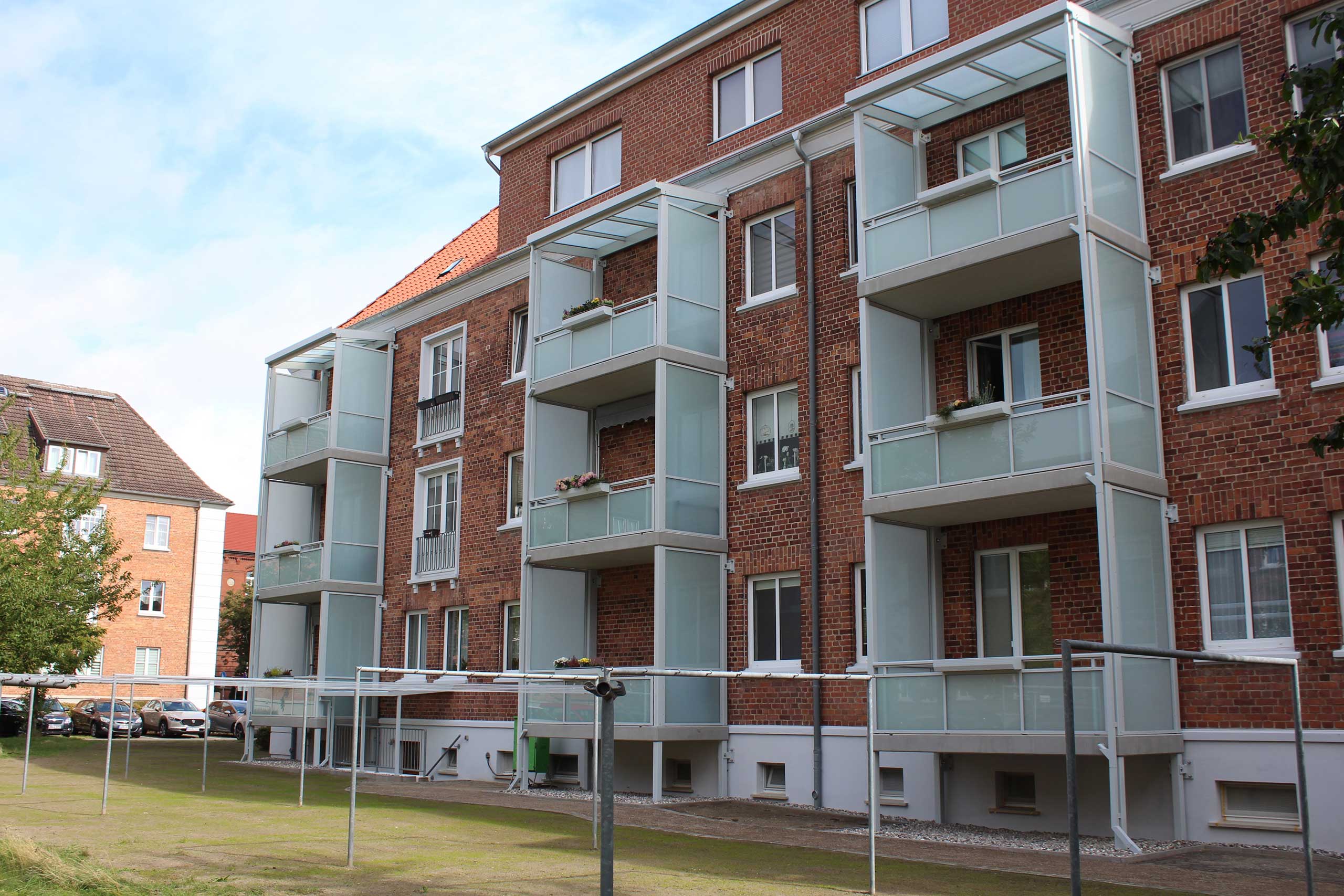 Saniertes Backsteinwohnhaus der AWG Güstrow in der Nordstadt mit neuen Balkonen und modernisierter Fassade.