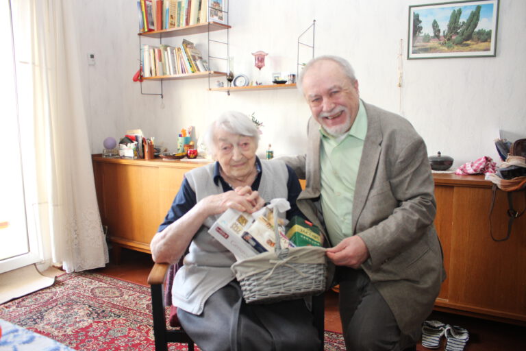 Das Bild zeigt die im Sessel sitzende Jubilarin Klara Fritz und den AWG-Aufsichtsratsvorsitzenden Dr. Manfred Müllner mit dem Präsentkorb.