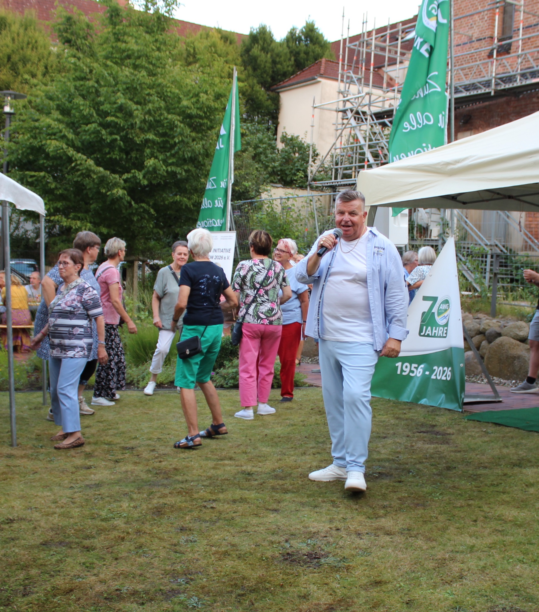 Auf dem Foto sind mehrere Personen zu sehen, die tanzen. Im Vordergrund ist Schlagerikone Frank beim Singen zu entdecken.