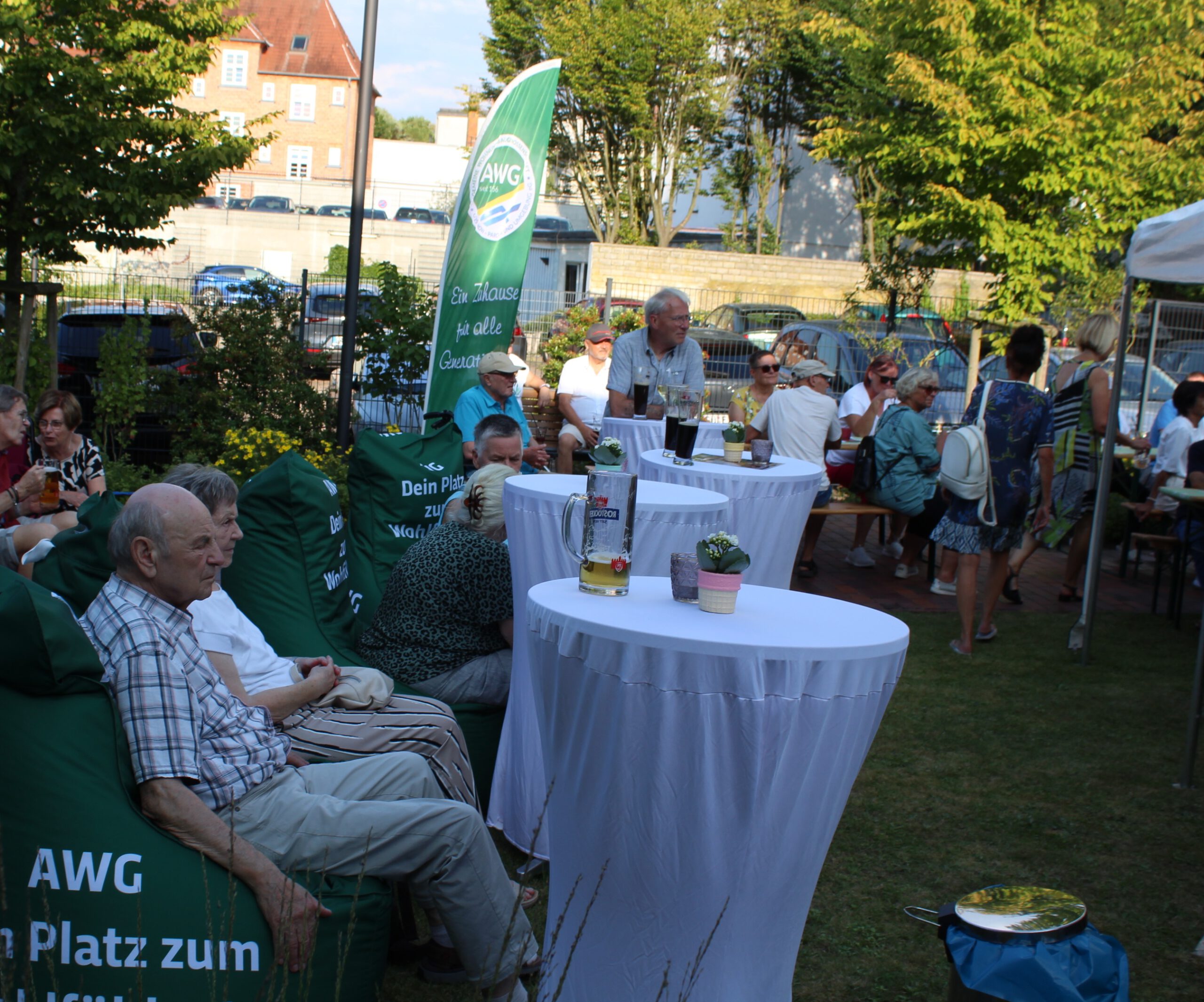 Das Bild zeigt Personen, die auf gr&uuml;nen Sitzs&auml;cken Platz genommen haben, die mit AWG-Werbung versehen sind.
