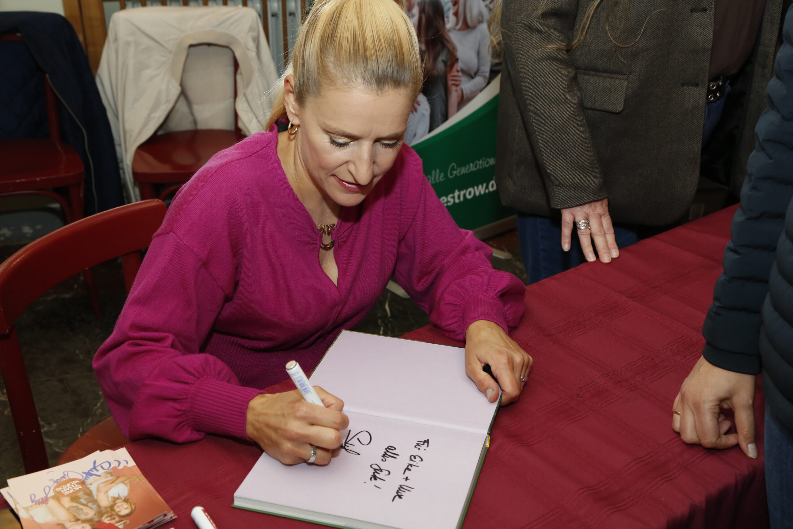 Das Foto zeigt Stefanie Hertel an einem Tisch sitzend beim Signieren eines ihrer B&uuml;cher .